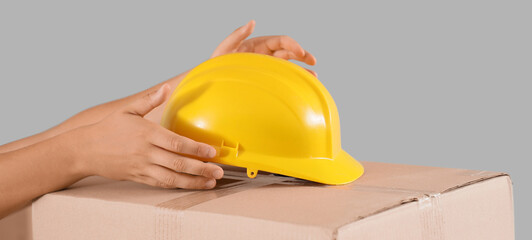 Male loader with hardhat on cardboard box in warehouse