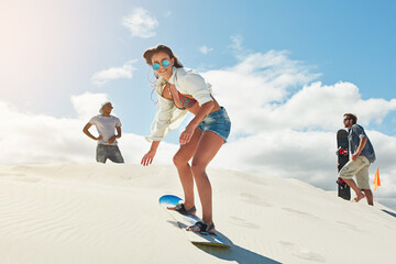 Sand boarding, friends or woman in desert for adrenaline experience, speed or slide downhill in sunglasses. Extreme sport, action or people with dune equipment, outdoor space or balance challenge © peopleimages.com