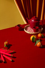 A red and gold Chinese New Year composition with red tea set and traditional fruits - tangerines. The clean styling leaves room for adding product visuals, space for design product and add text