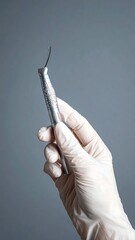 Close-up of a gloved hand holding a dental instrument
