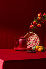 Traditional Chinese New Year setup with tea, fruits, and festive ornaments. The red color palette and clean background make it suitable for premium holiday branding. Vertical frame, space for design