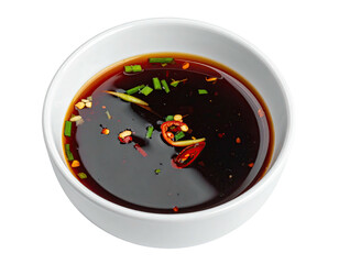 White bowl holding dark sauce, garnished with red pepper and chives