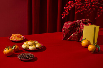 A festive Lunar New Year layout with traditional cakes, fruits, and gift elements on red table. Simple and clean background, space for adding product visuals or promotional text