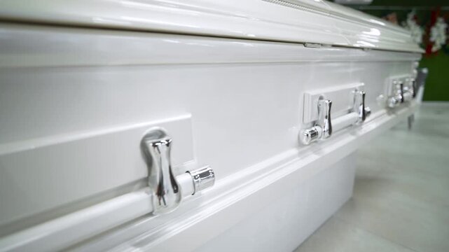 An expensive white glossy coffin is in the store. Funeral and farewell to the deceased.