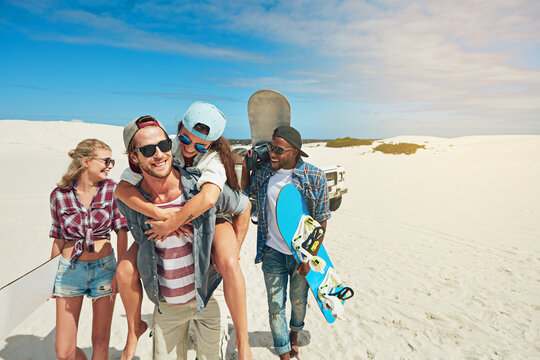 Hobby, sand board and space with friends outdoor on dunes for adventure activity or extreme sports. Happy, travel and vacation with group of sandboarding people in nature for bonding, holiday or trip