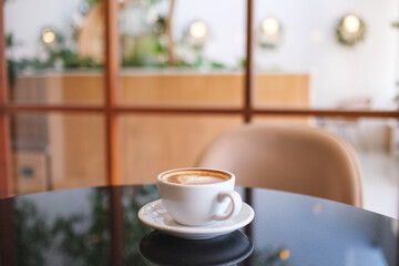 Closeup image of a white cup of hot coffee on the table in cafe