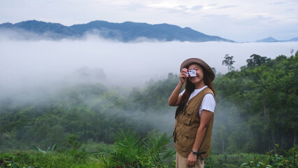 A female traveler taking photo of a greenery mountain views and the sea of clouds