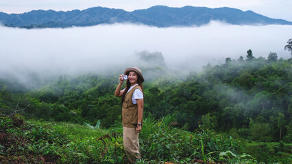 A female traveler taking photo of a greenery mountain views and the sea of clouds