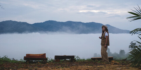 Portrait image of a female traveler with the greenery mountain views and the sea of clouds