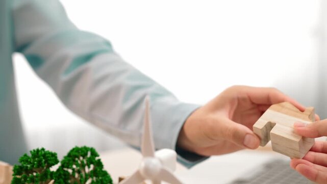 Excellent business people analyzing on eco house project at messy table with green energy using graph with windmill, home, tree model to decrease carbon usage, save earth. Focus on hand. Delineation.