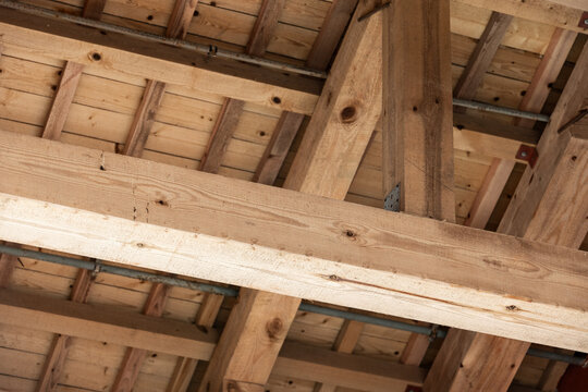 A close view of heavy timber beams and roof framing in a building under construction