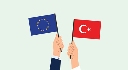 Hands holding flags of the European Union and Turkey representing international relations, diplomacy, and political cooperation.
