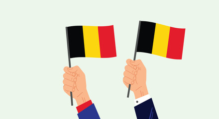 Hands holding two flags of Belgium representing national pride, celebration, and patriotic events during public holidays or festivals.