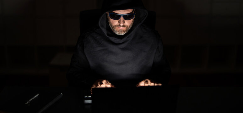 Hacker attack. Hacker gamer at night in office. Cyber attack. Cyber criminal and stolen personal data. Digital thief. Hacker programmer in hoodie at office laptop, gaming. Cyber intrusion - Powered by Adobe