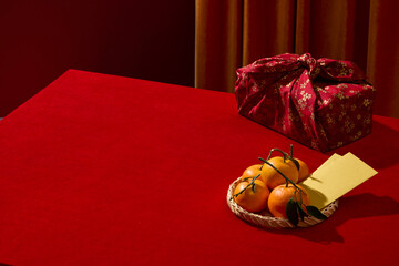 A Lunar New Year setup with wrapped gifts, tangerines and lucky envelopes decorated on red table. Red and gold color creates a warm festive mood, blank for product presentations.