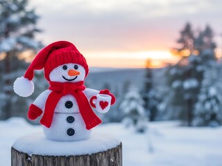 A cute knitted snowman wearing a red hat and scarf holds a heart mug in a snowy winter forest