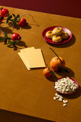 Lunar New Year scene with fruits, cakes,, pumpkin seeds and lucky envelopes decorated on yellow background. Traditional holiday of Chinese. Space for design