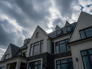 Dramatic Low Angle View of a Large Modern Luxury Home with Gabled Roof Under a Stormy Cloudy Sky