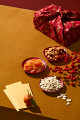 Top-down style Chinese New Year scene with traditional snacks, fruits jam, red gift box and lucky envelopes. Ideal for festive marketing visuals, design product and add text