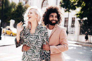 Naklejka premium Beautiful fashion woman and her handsome elegant boyfriend in beige suit. Sexy blond model in summer suit clothes. Fashionable smiling couple posing in street Europe. Brutal man and female outdoors