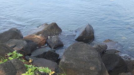 Rocks are arranged on the edge of the beach, the sea water is calm