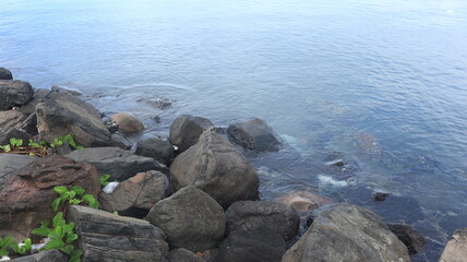 Rocks are arranged on the edge of the beach, the sea water is calm