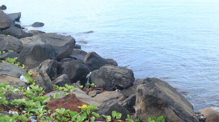 Rocks are arranged on the edge of the beach, the sea water is calm