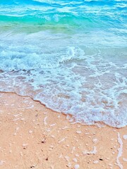 Blue and white waves on a brown beach.