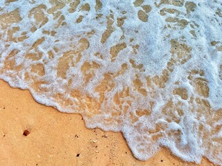 Blue and white waves on a brown beach.