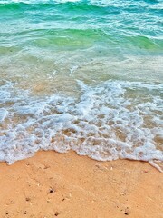 Blue and white waves on a brown beach.