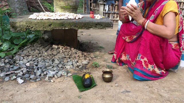 Odia Woman Performing Basumati Snana Mother Earth Ritual During Raja Festival in Odisha, India. The ritual honors Mother Earth (Basumati) by decorating a grinding stone (Shilpua) with flowers