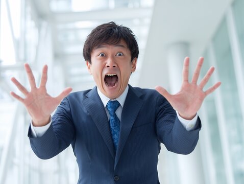 両手を大きく広げて驚きの表情を見せるスーツ姿の男性が感情を全力で表現するビジネスシーン