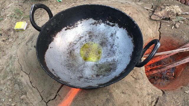 Pouring Cooking Oil into Traditional Iron Kadhai on Wood Fire, Outdoor Village Cooking Preparation, Rustic Indian Kitchen, 4K Stock Footage