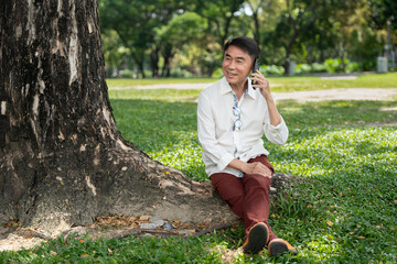 Asia elderly man relax with smart phone in the park
