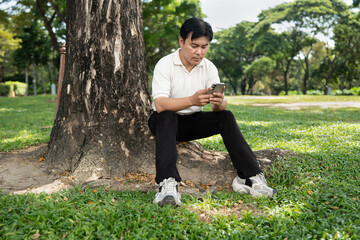 Asia man relax with smart phone in the park