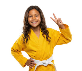 Smiling young girl in yellow martial arts gi showing victory sign