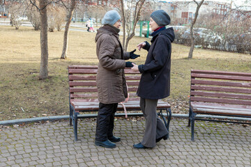 Two women having a conversation in a park. Social worker visiting and caring for elderly woman. Intergenerational communication and family support concept