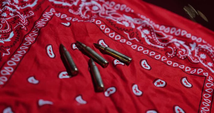 Cinematic close-up of bullet cartridges placed on a red bandana&mdash;concept for gang conflict, street violence, crime symbolism, and law enforcement investigations.