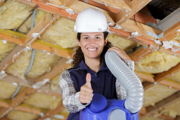 female builder with air condiutioning unit holding thumbs-up