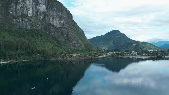 Panning drone aerial of Llifen on Ranco Lake with dramatic rocky cliffs, mountains backdrop, reflections, and Chilean wilderness