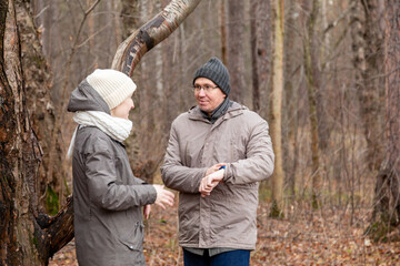 Woman and man talking outdoor in forest. Mature couple communicating during fall or winter cold season stroll. Happy relationship concept.