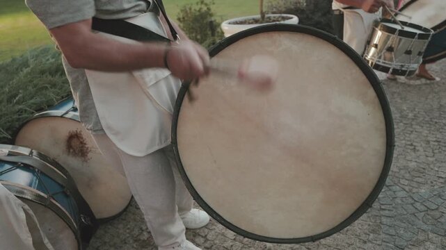 Musicians striking large drums during traditional outdoor performance