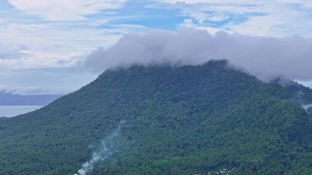 Aerial footage of Mt Paco in Surigao del Norte, Philippines, featuring cloud-shrouded mountain terrain and forested slopes. Drone view highlights natural landscape and elevation under overcast skies.