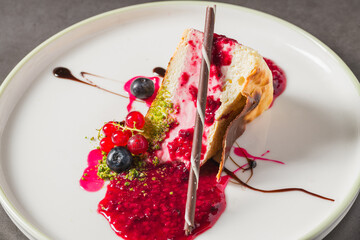 Cheesecake slice topped with fresh berries and vibrant sauce