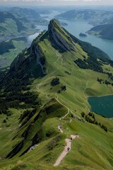 Aerial View of Lush Green Mountain Ridge with Hiking Trail and Lake Landscape Under Sunny Skies