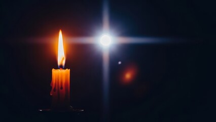 Fototapeta premium A single lit candle with dripping wax and a bright lens flare in a dark room.