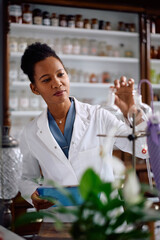 Black female pharmaceutical researcher working in drugstore.