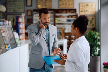 Distraught man talking to his pharmacist in drugstore.