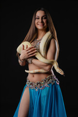 Woman dances with a snake in a dark setting showcasing movement and connection