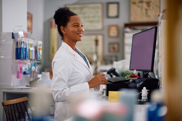 Happy black female pharmacist working in drugstore.